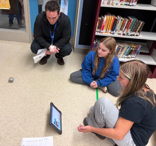 two students work on coding while being supervised
