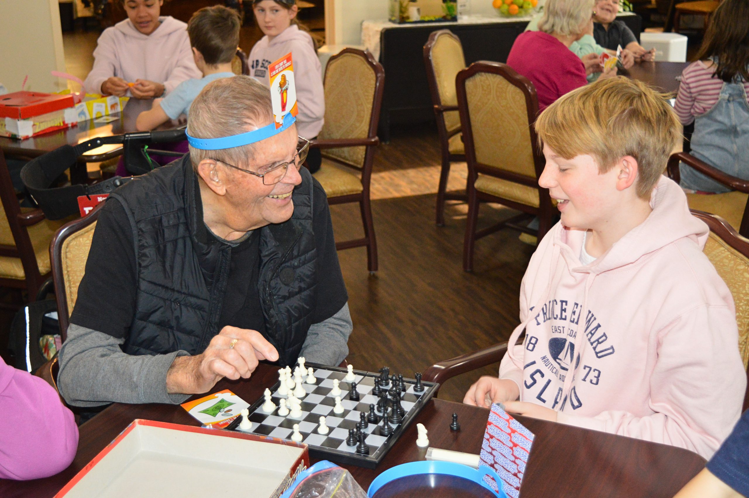 Older man laughing as he plays games with student.