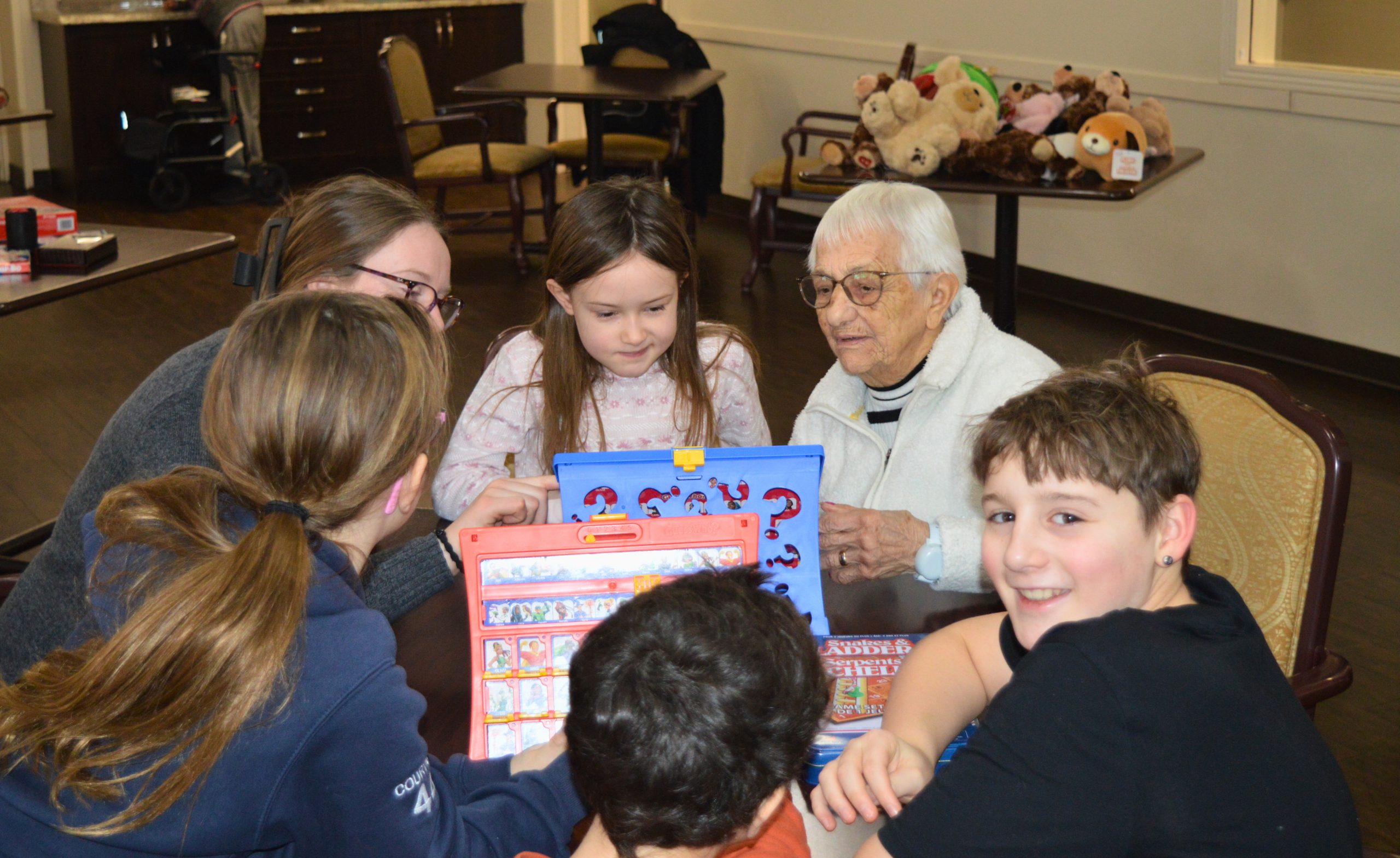Older woman surrounded by children, all playing a game.